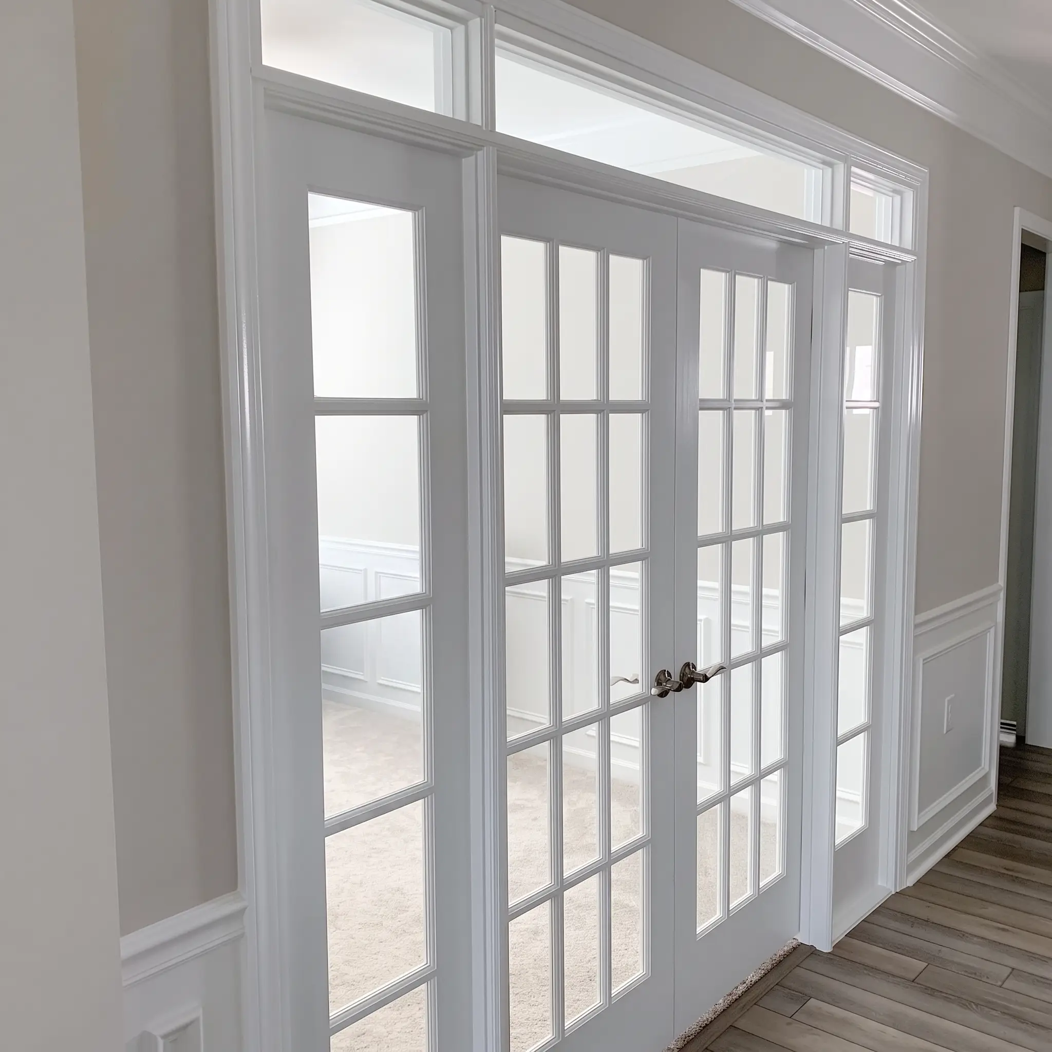 Newly installed white French doors with a transom and clean trim by JND Home Solutions
