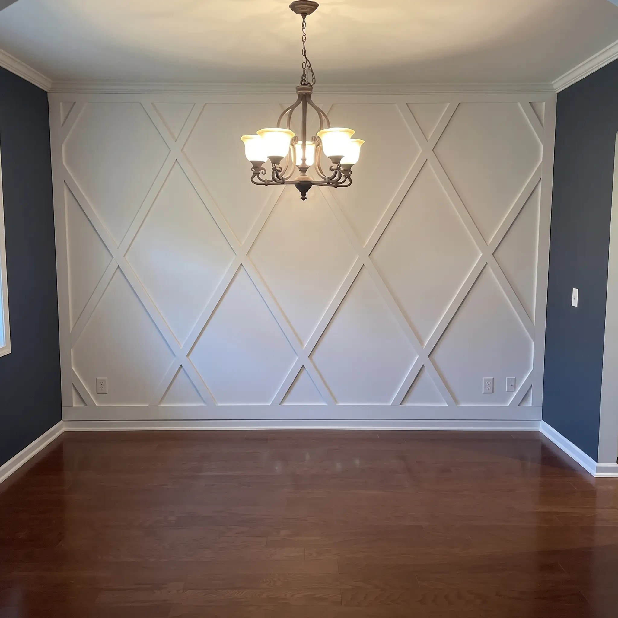 White diamond-lattice accent wall built against a navy dining room by JND Home Solutions