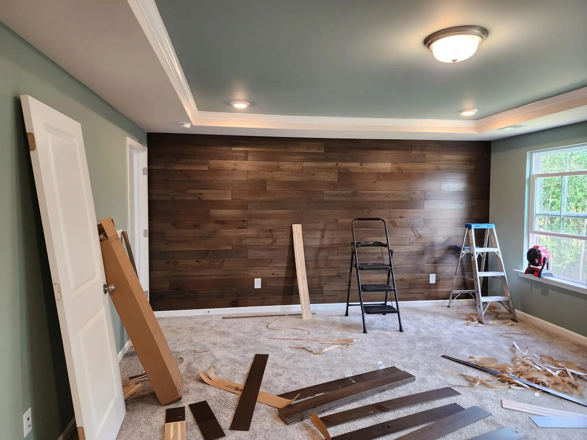 Dark wood plank accent wall going up in a bedroom with a tray ceiling