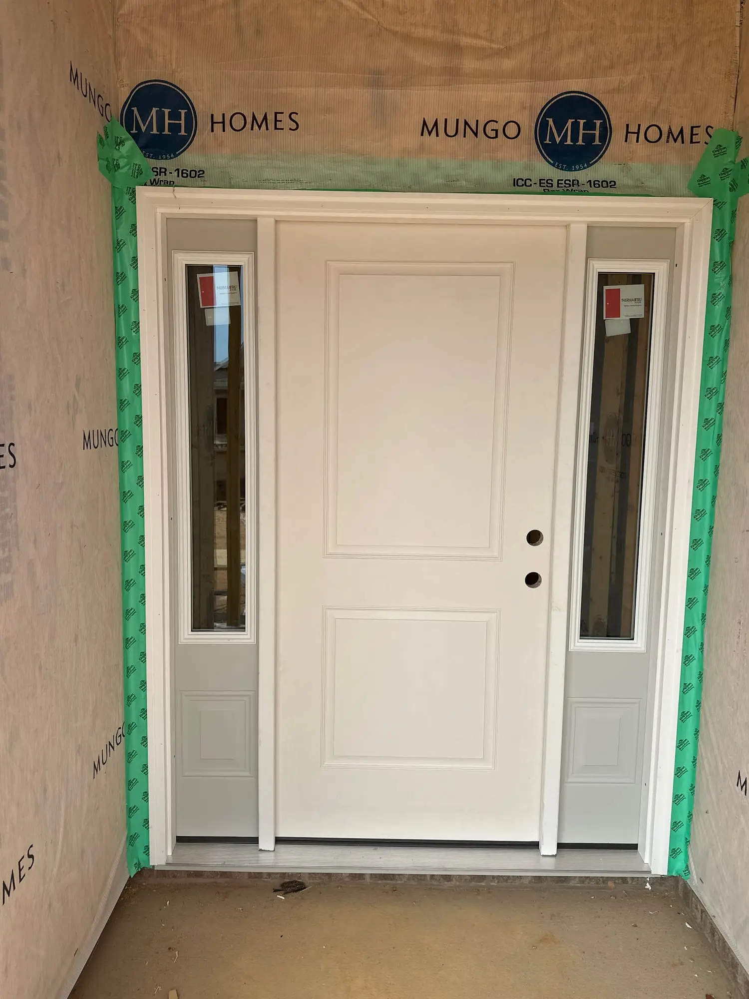 New front entry door with glass sidelights, hung and squared in a new build