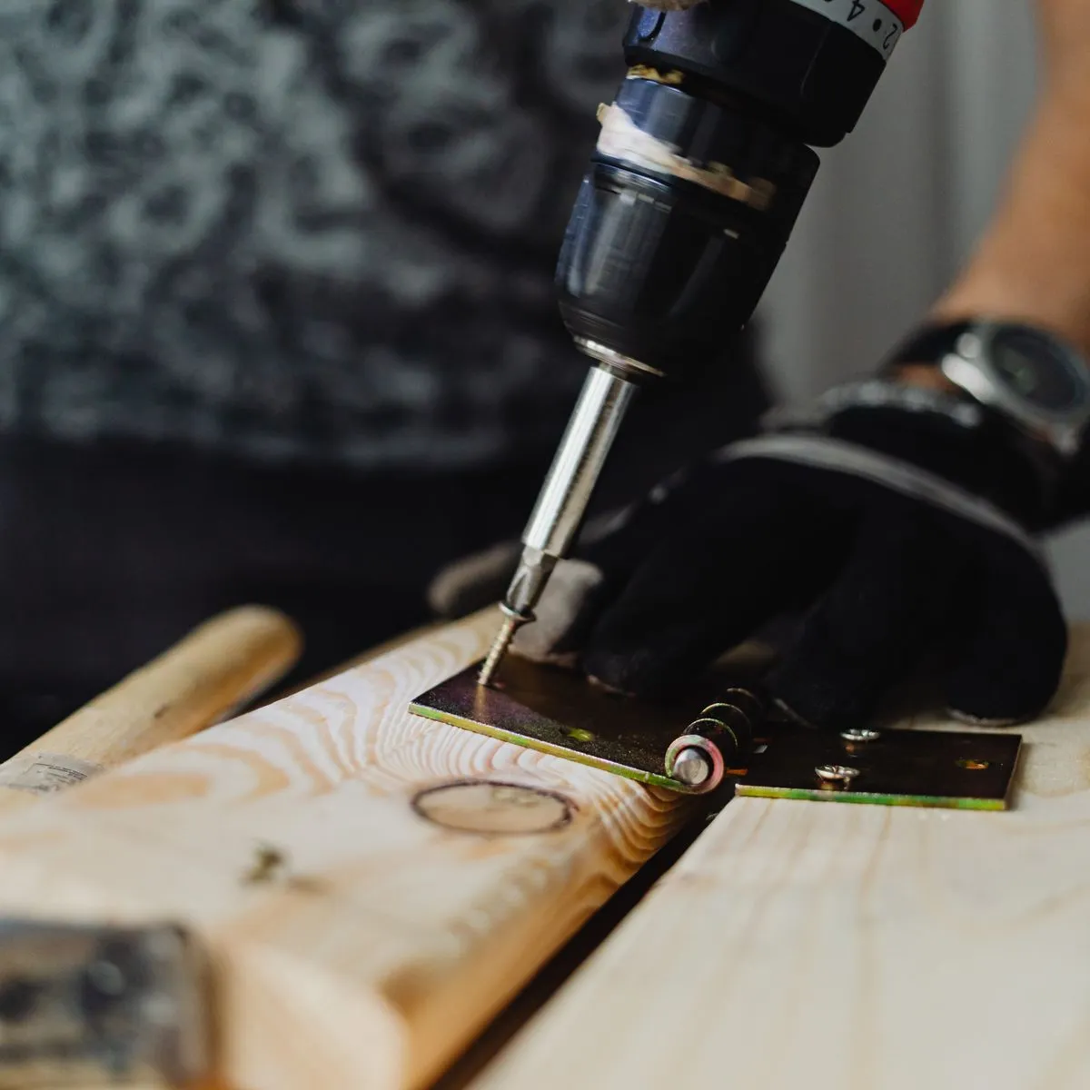 Close-up of hands using a cordless drill to fasten hardware to a board