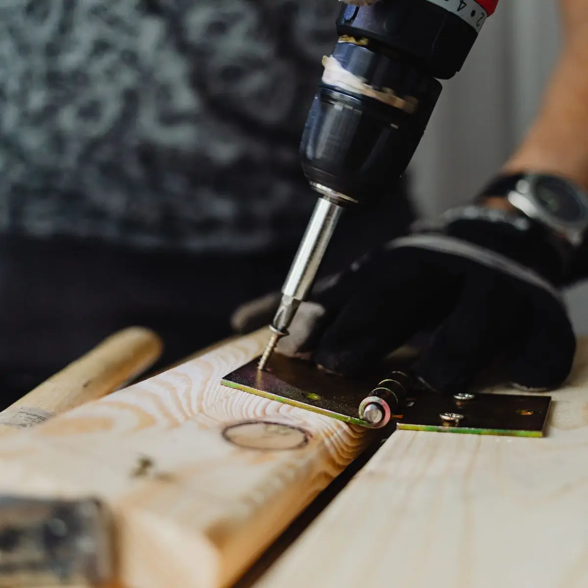 Close-up of hands using a cordless drill to fasten hardware to a board